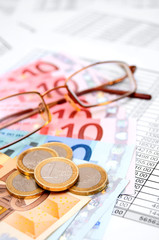 Glasses, euro and coins on documents.
