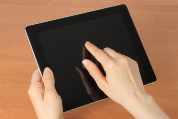 Hand toching tablet PC on wooden background .