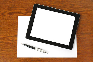 Tablet PC, paper and pen on wooden background .