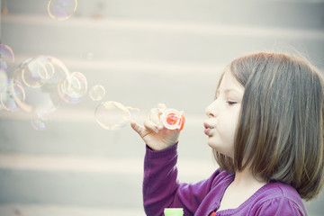 Young girl blowing soap bubbles