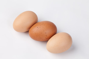 Three freshly harvested brown eggs on a white background 