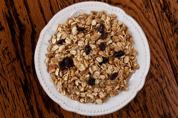 Top view of a bowl of homemade granola with oats, almonds, organic raisins, and walnuts