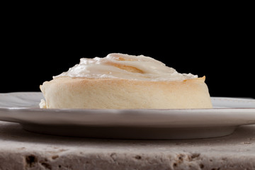 Fresh out of the oven homemade giant cinnamon roll isolated on black