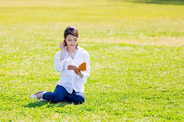 young asian woman reading book in the park