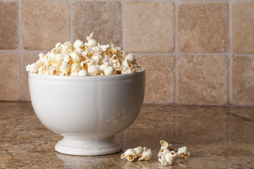 Vintage ceramic bowl with olive oil organic popcorn on granite counter with popcorn pieces to the side