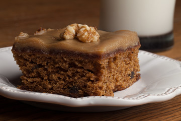 Macro shot of carrot cake topped with a walnut next to a fresh glass of cold 1% milk