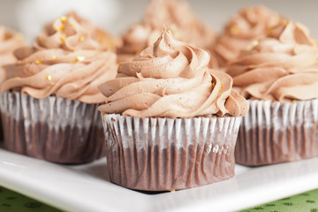 Platter of St. Patrick's Day Pot of Gold cupcakes - chocolate cake with a rich salted caramel center topped with chocolate buttercream and edible gold stars