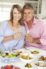 Mid age couple enjoying meal at home