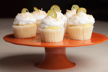 Retro vintage orange platter with Coconut Key Lime Cupcakes - Coconut cake with a key lime filling topped with a light 7 minute frosting, toasted coconut, and a slice of candied key lime
