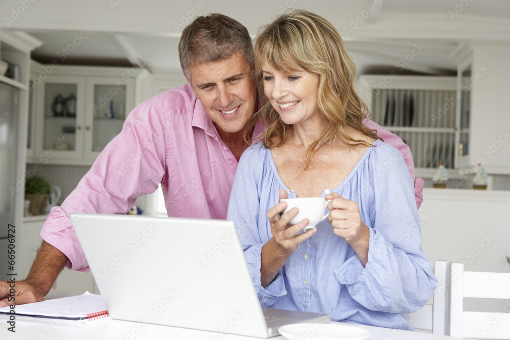 Wall mural mid age couple working at home on laptop