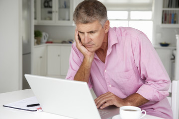 Fototapeta na wymiar Mid age man working on laptop at home