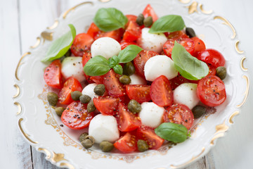 Salad with cherry tomatoes, mozzarella, capers and green basil
