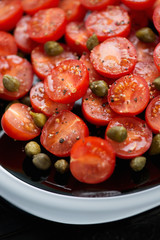 Salad with cherry tomatoes, capers and spices, vertical shot