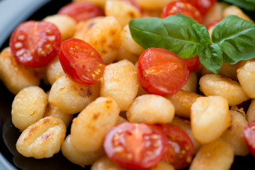 Roasted gnocchi and cherry tomatoes with green basil, close-up