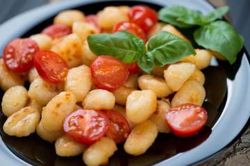 Fried italian gnocchi with red cherry tomatoes on a glass plate