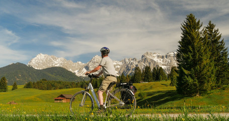 Fototapeta premium Fahrradfahrer betrachtet malerische Landschaft der Alpen