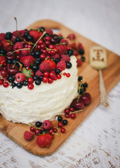 Cake with fresh berries and white glaze in woman's hands