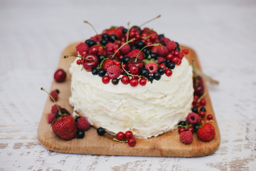 Cake with fresh berries and white glaze in woman's hands