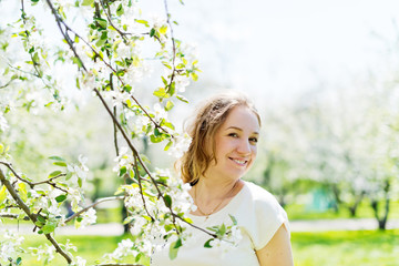 beautiful young brunette woman standing near the apple tree on a