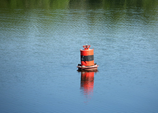 Red buoy on quiet river with resting on it ducks on summer day
