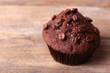 Chocolate muffin and coffee grains on wooden background