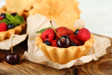 Tasty tartlets with berries on wooden table