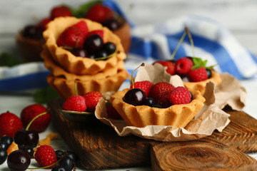 Tasty tartlets with berries on wooden table