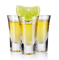 Three gold tequila shots with lime isolated on white