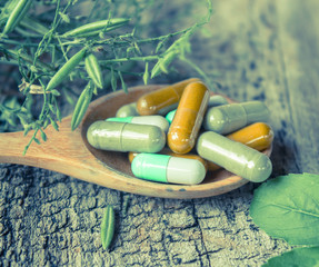 Herb capsule on wooden spoon