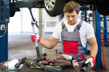 Young mechanic with tools in a car workshop