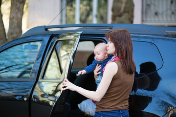 Young mother with her baby getting into a car