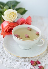 Cup of tea with dried roses and fresh roses