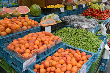 Fruit and vegetables lie in boxes on a market counter