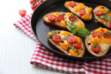 Tasty bruschetta with tomatoes in pan, on table