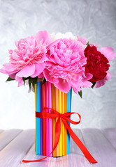 Beautiful flowers in colorful pencils vase on grey background