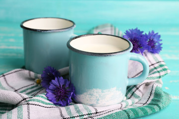 Cups of milk and cornflowers on wooden table