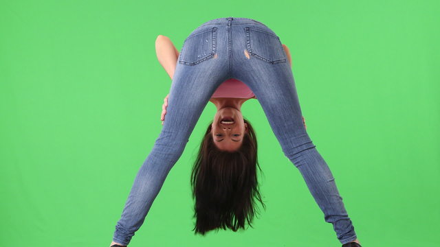 Back view of young woman in tight jeans bending over and smiling