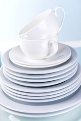 Set of white dishes on table on light background