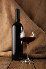 Bottles of wine with glass on burlap background