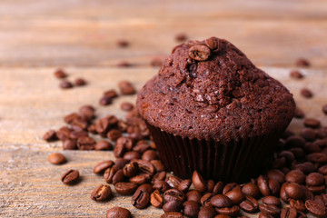 Chocolate muffin and coffee grains on wooden background