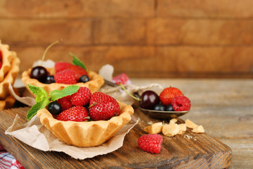 Tasty tartlets with berries on wooden table
