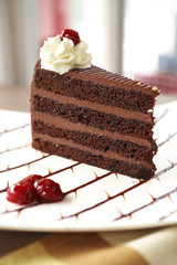 close up dark chocolate cake and cherry on white dish