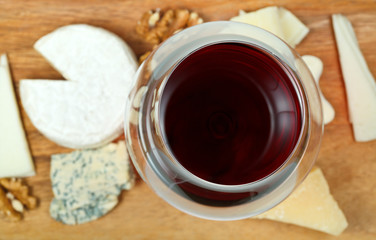 top view of glass of red wine and various cheeses