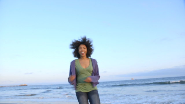 Portrait of woman running and smiling at beach