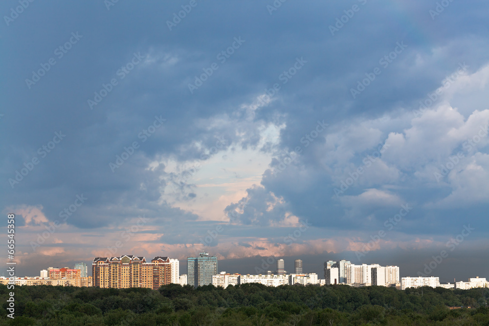 Wall mural dark rainy clouds in sunset sky over city