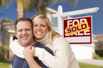 Couple in Front of Sold Real Estate Sign and House