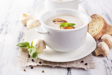 Mushroom soup in white pots, on napkin, on wooden background