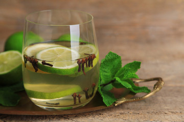 Fresh summer drink with lime and cloves in glass,