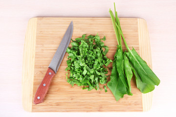 Chopped greens with knife on cutting board on table