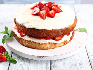 Delicious biscuit cake with strawberries on table close-up
